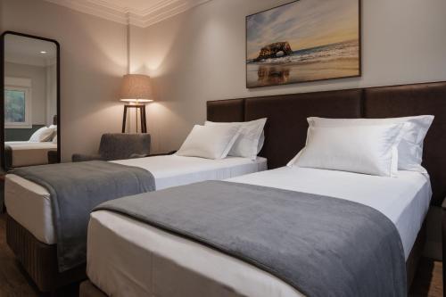 a hotel room with two beds and a mirror at Hotel Kindermann Chapecó - Hotel Novo in Chapecó