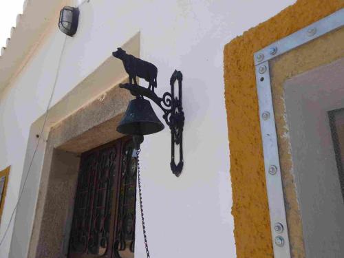 a black cat on a bell next to a door at Herdade Joana Dias by PortusAlacer in Arronches