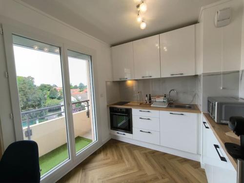 a kitchen with white cabinets and a large window at Agréable Studio Chantilly avec balcon et parking securisé in Pau