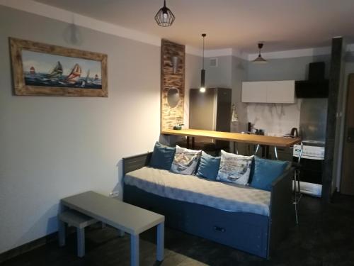 salon z niebieską kanapą i kuchnią w obiekcie Apartamenty Sielawa w mieście Mikołajki