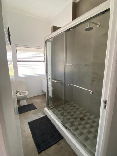 a glass shower in a bathroom with a toilet at Barefoot at Calypso Beach in Langebaan