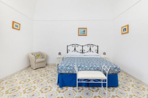 a white bedroom with a bed and a chair at Il Merlo Capri in Capri