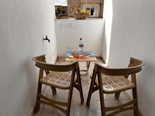 a table with a bottle of water and two chairs at Appartement au calme in Bir Kassa