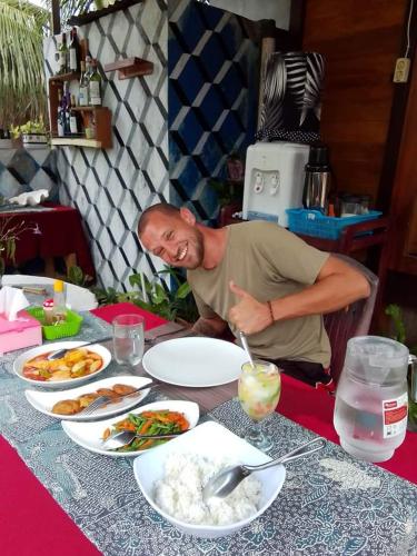 a man sitting at a table with plates of food at Naca Homestay in Manado