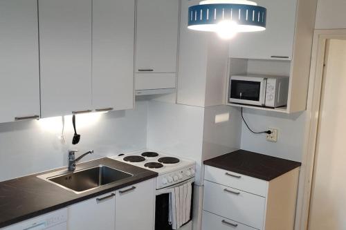 a white kitchen with a sink and a microwave at Nice 3-room-apartment next to Old Rauma & stadiums in Rauma