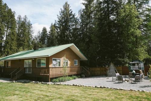Una pequeña cabaña con techo verde en un patio. en Vibrant Forest Retreat - Game Room, Spa, Fire Pit - Sleeps10, en Spirit Lake