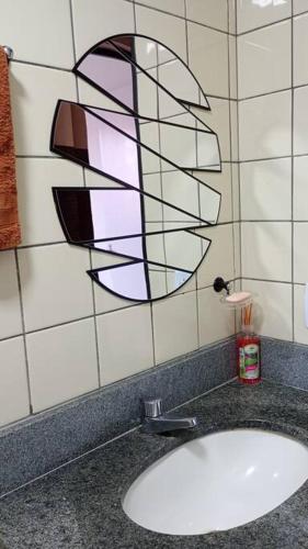 a bathroom sink with a painting on the wall at Apto Completo Aparecida de Gyn in Aparecida de Goiania
