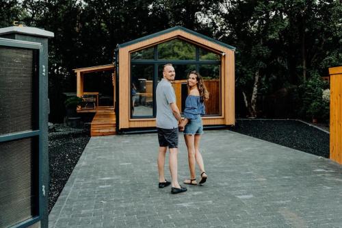 a man and woman standing in front of a tiny house at Maroska Forest Cabin & Wellness in Kismaros