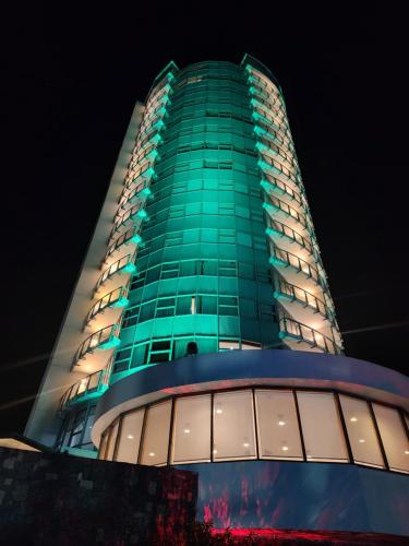 a tall green building with windows at night at Hotel Humboldt in Los Mecedores