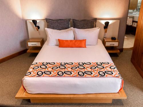 a bedroom with a large bed with an orange pillow at Hotel Humboldt in Los Mecedores