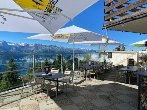 a patio with tables and chairs with mountains in the background at Berggasthaus Rigi-Burggeist in Gersau