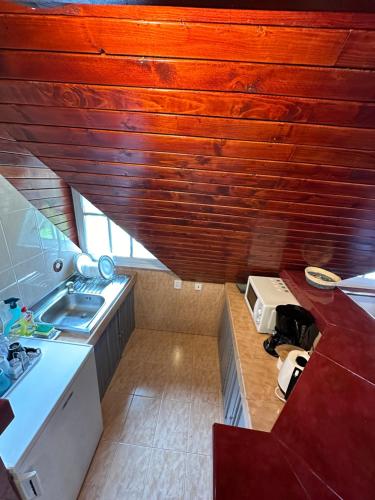 a small kitchen with a sink and a wooden ceiling at Pine Peak in Predeal
