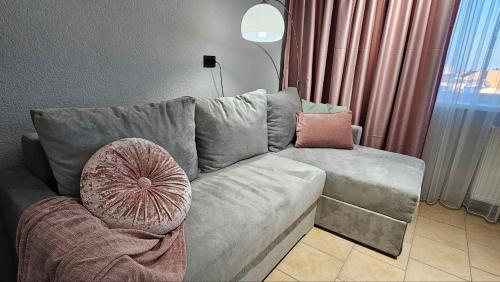 a living room with a gray couch with a pink pillow at Blue Apartment in Mukacheve