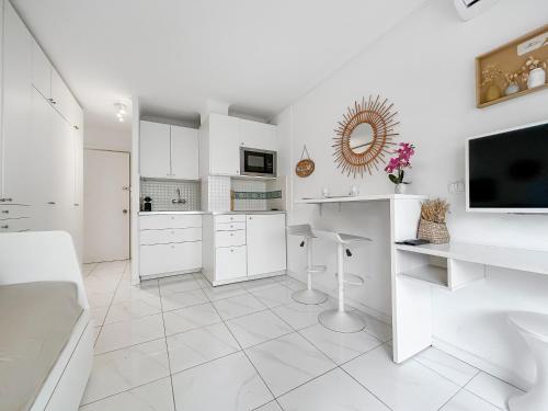 Il comprend une cuisine blanche avec des placards blancs et une télévision. dans l'établissement Studio lumineux, WIFI à deux pas de la Croisette, à Cannes