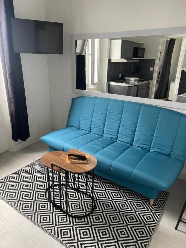 - un canapé bleu dans le salon avec une table basse dans l'établissement Appartement cosy proche gare, à Angoulême