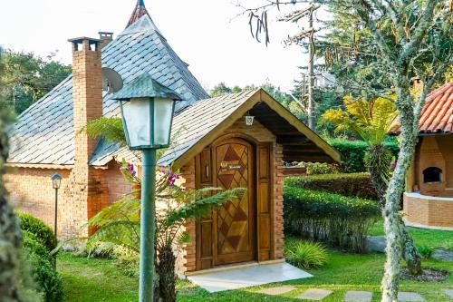 a small house with a wooden door and a street light at VELINN Pousada Torre Branca in Monte Verde