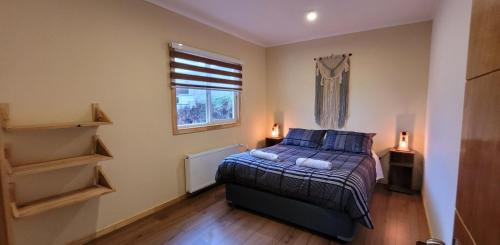 a bedroom with a bed with blue pillows and a window at Terrke in Punta Arenas