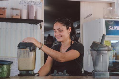 a woman is standing in front of a blender at La Negra Surf Hotel in Nosara