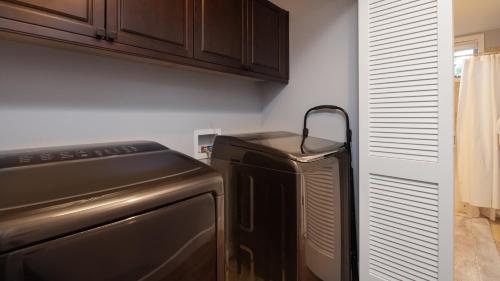 a kitchen with a stove and a refrigerator at SEA GLASS Stunning 3BR KaMilo Home with Heated Pool and Best View in Waikoloa