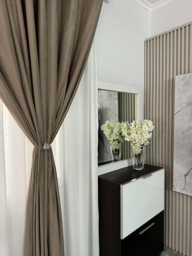 a room with a curtain and a vase of flowers at Angel's Studio Apartments in Tirana