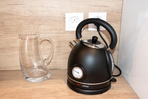 une bouilloire à thé noir sur un comptoir à côté d'un verre dans l'établissement L'instant Troyen, à Troyes