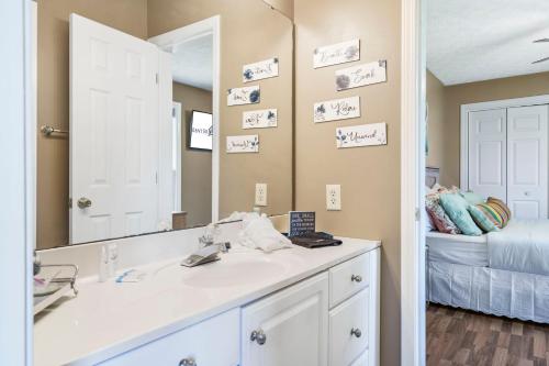 a bathroom with a sink and a mirror and a bed at Bee Creek Poolside in Branson