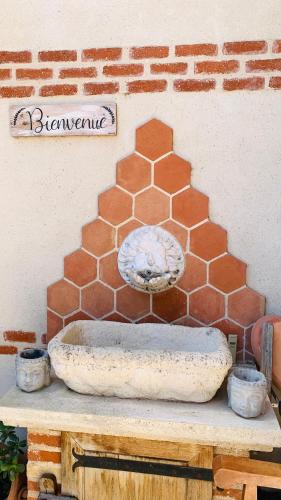 un mur en briques avec une fontaine au-dessus d'une table dans l'établissement Chambres d'Hôtes Au Clos Saint Georges, à Saint-Jory