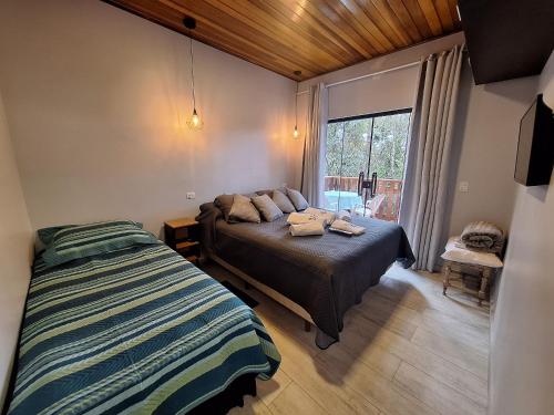 a bedroom with a bed and a window at Chalé Dália - Recanto Veky in Campos do Jordão