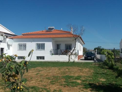 a white house with a car parked in the yard at Belamandil Garden ,family holidays ,caminho do torrejao olhao in Olhão