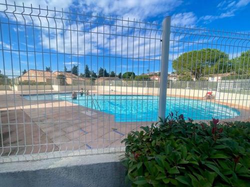 une piscine vue à travers une clôture dans l'établissement Charmante Maison, Terrasse,parking domaine du pins, piscine, à Fréjus