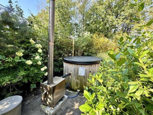 a woodburning stove in a garden with trees and bushes at Holiday Home Maridu Wellness in Arnhem