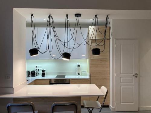 une cuisine avec plusieurs lumières suspendues au plafond dans l'établissement Garden floor apartment located next to the beach with a car park, à Biarritz
