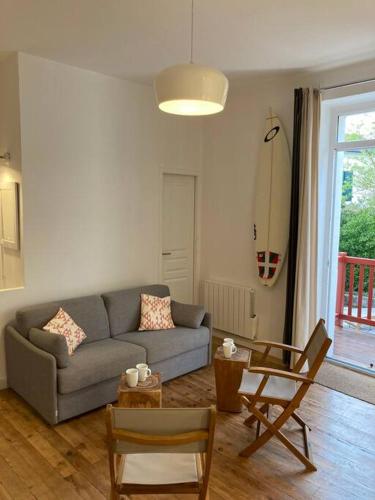 - un salon avec un canapé, des chaises et une planche de surf dans l'établissement Garden floor apartment located next to the beach with a car park, à Biarritz