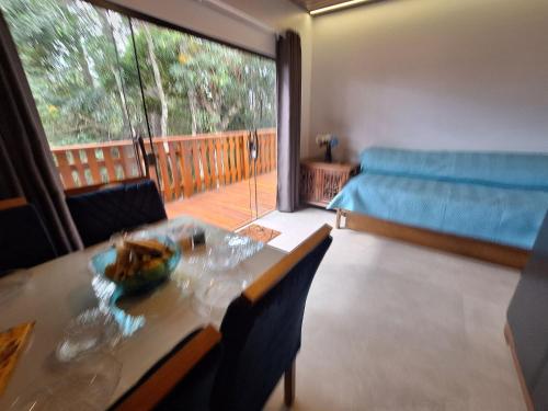 a living room with a table and a large window at Chalé Jasmim - Recanto Veky in Campos do Jordão