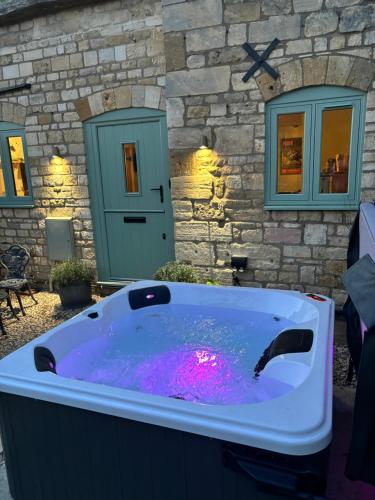 a hot tub in front of a stone building at The Old Forge in Cheltenham