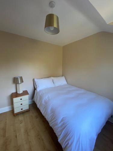 a bedroom with a white bed and a night stand at Cozy 2 bedroom townhome in Donegal