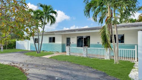 a house with a blue fence and palm trees at Sunset Oasis with Movie Theatre, Heated Pool & Game Room in Pompano Beach