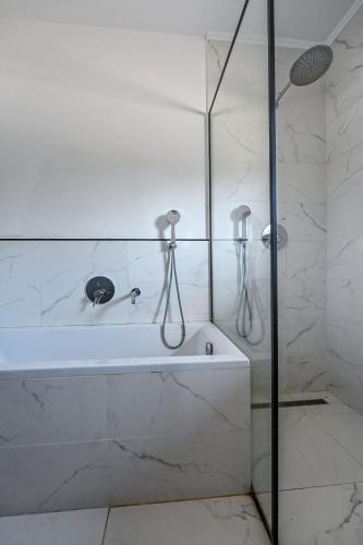 a white bathroom with a tub and a shower at Glamping Home in Bukovik