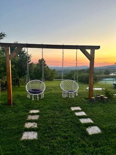 two swings in a field with the sunset in the background at Glamping Home in Bukovik