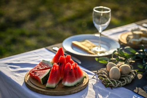 a table with a plate of watermelon and a glass of wine at Glamping Home in Bukovik