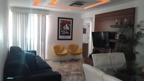 a living room with a couch and a tv at Apartamento Paraiso Litoral in São Pedro da Aldeia