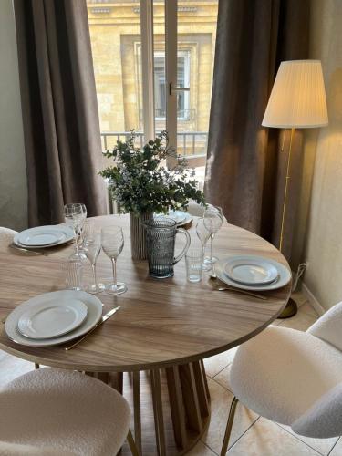 une table en bois avec des assiettes et des verres à vin dessus dans l'établissement Royal Home, hypercentre Reims avec vue Cathédrale, à Reims
