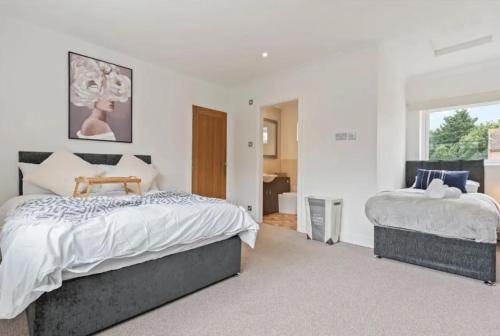 a white bedroom with two beds and a window at Charming 4 Bedroom 3 Bathroom House - Sleeps up to 9 - Pool Table, Sky TV & Netflix, Fast WiFi, Driveway Parking & Self-Check-In By Yoko Property in Great Malvern
