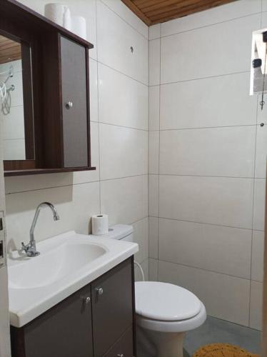 a white bathroom with a toilet and a sink at Casa aconchegante no centro in Bonito