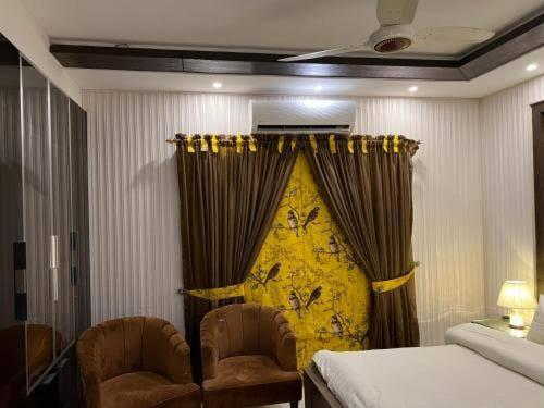 a bedroom with a bed and two chairs and a curtain at Gulshan Guest House Furnished Portions in Karachi