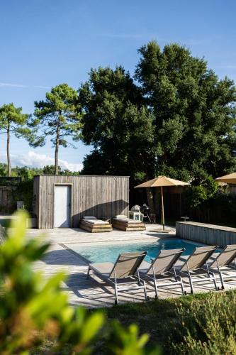 un groupe de chaises assises à côté d'une piscine dans l'établissement Villa Contis Plage, à Lit-et-Mixe
