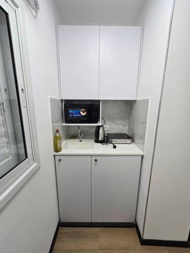 a small kitchen with white cabinets and a microwave at Ryo 39 דירת נופש מושלמת מרחק 5 דקות מחוף הים in Bat Yam