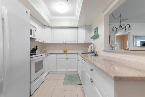 a kitchen with white cabinets and a sink at Spacious 3BR Beachfront Condo with Balcony & Parking in Satellite Beach