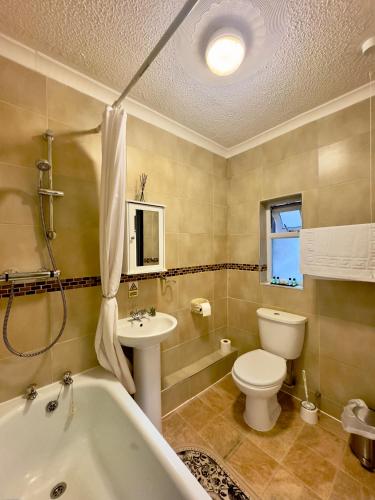 a bathroom with a tub and a toilet and a sink at Coastal Park Accommodation in Llanelli