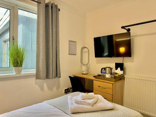 a hotel room with a bed and a desk and a tv at Coastal Park Accommodation in Llanelli